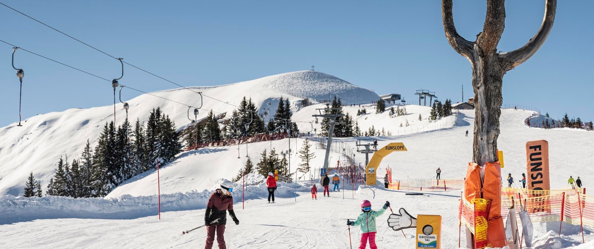 Eine Frau fährt mit einem kleinen Kind im Familien-Skiurlaub im Großarltal durch den Funpark