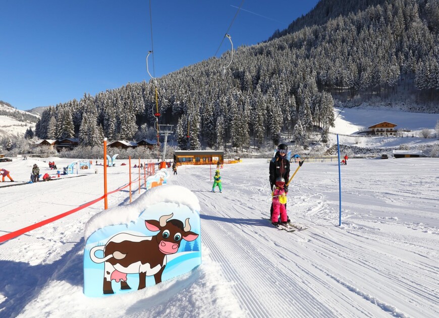 Familie mit Kindern im Skiurlaub auf der Erlebniswiese Fischbacher im Großarltal, Salzburger Land.